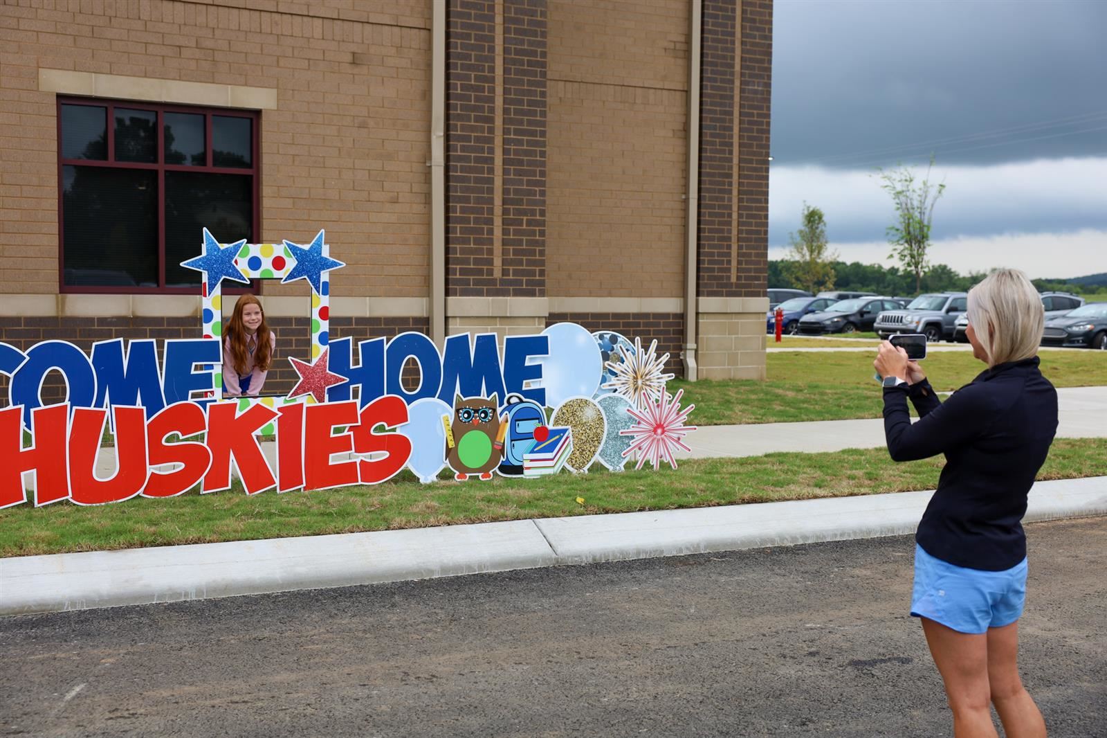 mom taking a photo of girl in front of welcome to arrington sign